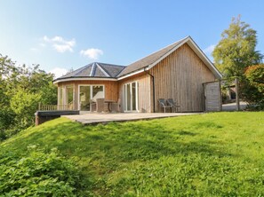 A two-story wooden house with a covered patio and a large barn-like structure. - Glen Lochay Lodge (Killin)