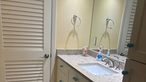 A bathroom with a sink, mirror, and cabinets. - Gulf-front paradise in Springtime on lovely Longboat Key 2/2 -2 pools,pickleball (Longboat Key)