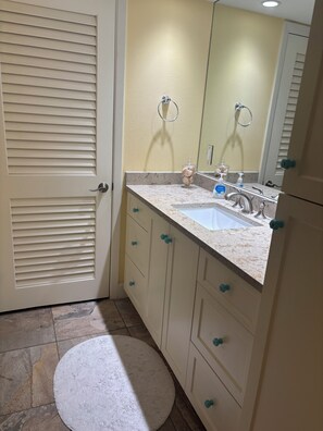 A bathroom with a sink, mirror, and cabinets. - Gulf-front paradise in Springtime on lovely Longboat Key 2/2 -2 pools,pickleball (Longboat Key)