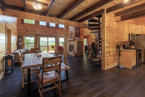 L’intérieur d’un chalet en bois comprend un coin repas, une cuisine et une cheminée en pierre.