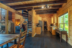 Ein Interieur einer Holzhütte mit Essbereich, Küche und einer Wendeltreppe.