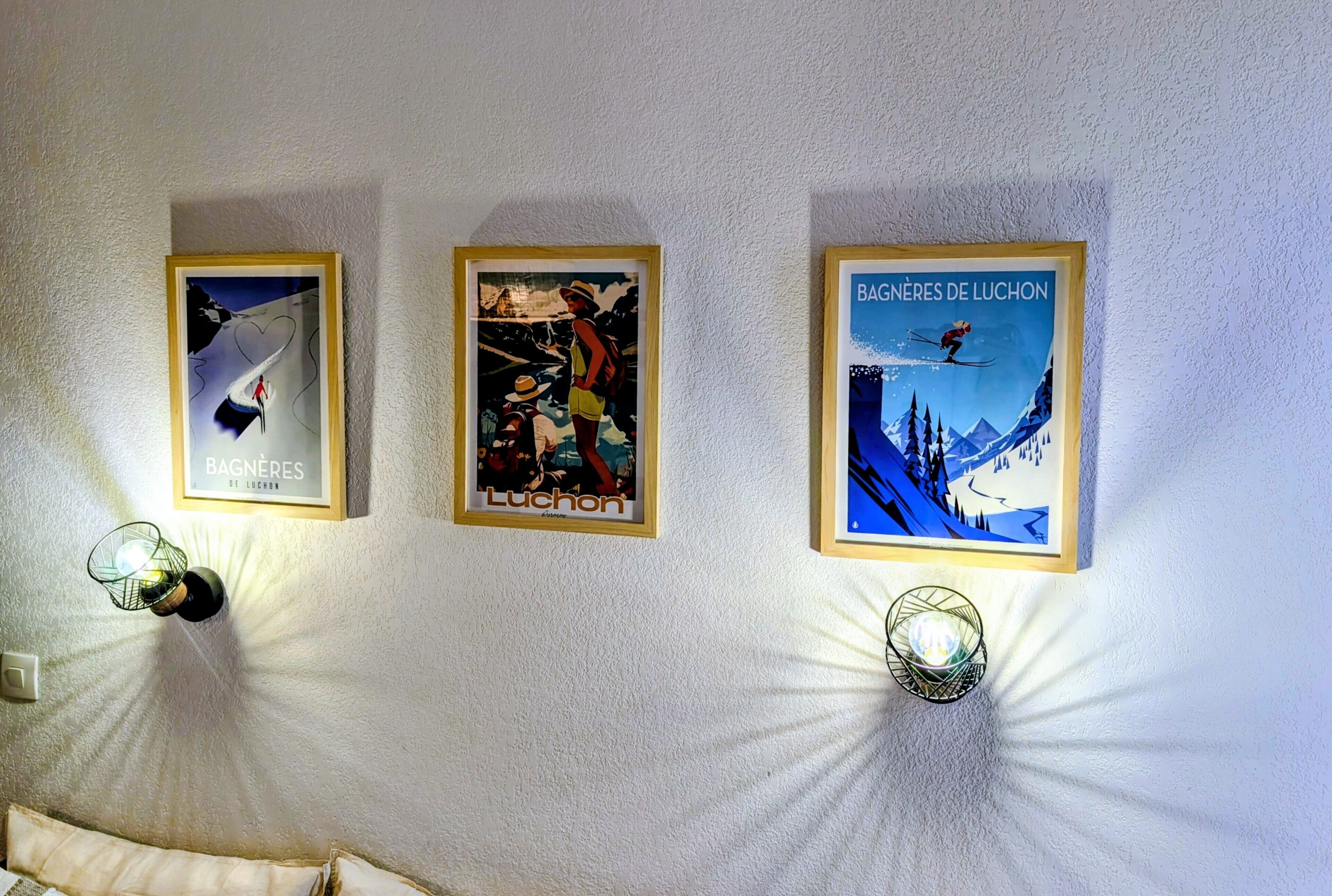 Drie ingekaderde posters aan een muur, elk met verschillende wintersporttaferelen.