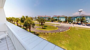 A view from a balcony overlooking a roundabout with palm trees, a stop sign, and a building with a water tower labeled 'LASTIN PORT BEACH'. - Great Location Seacrest 315B! (Fort Walton Beach)
