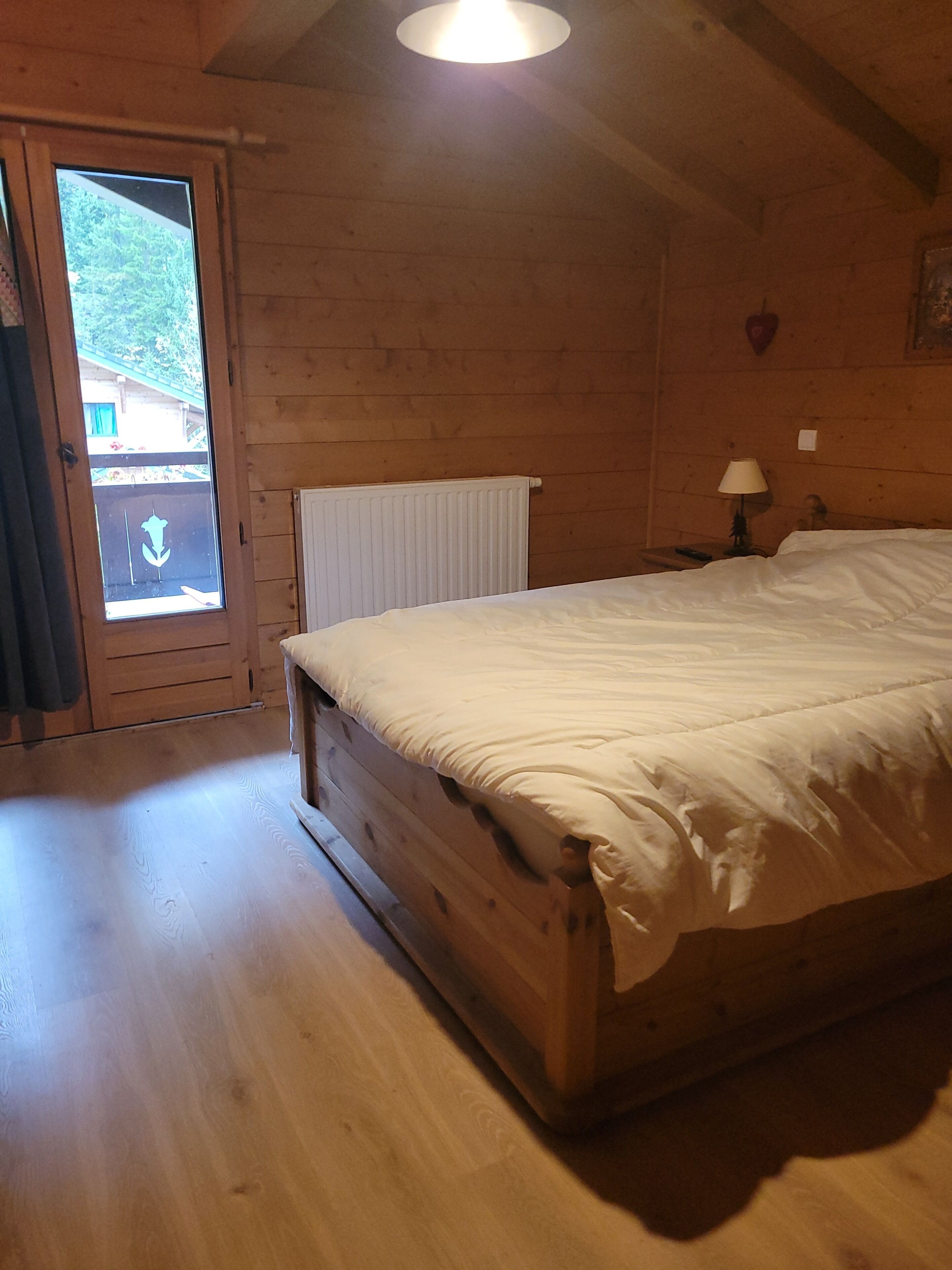 Une pièce en bois avec un lit, un radiateur et une fenêtre.