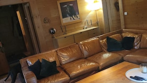 Ein gemütliches Wohnzimmer mit Ledersofa, Couchtisch und Holzboden.