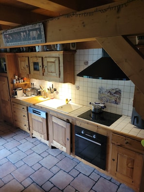 A kitchen with wooden cabinets, a black stove, and a tiled backsplash. - Delightful 5-bedroom chalet in Châtel perfect for your getaway (Châtel)