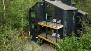 A modern black house with multiple floors, large windows, and a balcony with chairs. - Spacious 4BR mountain-view retreat near Old Town Park City. (Park City)