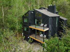 A modern black house with multiple floors, large windows, and a balcony with chairs. - Spacious 4BR mountain-view retreat near Old Town Park City. (Park City)