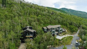 A modern two-story house with a large deck, surrounded by dense forest and hills. - Spacious 4BR mountain-view retreat near Old Town Park City. (Park City)
