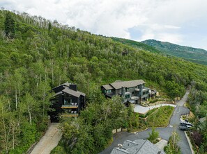 A modern two-story house with a large deck, surrounded by dense forest and hills. - Spacious 4BR mountain-view retreat near Old Town Park City. (Park City)