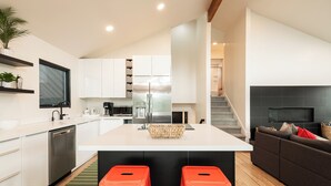 A modern kitchen with white cabinets, a stainless steel refrigerator, and a central island with stools. - Spacious 4BR mountain-view retreat near Old Town Park City. (Park City)