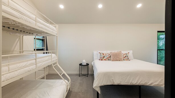 A bunk bed room with a single bed, a small table, and a window with a view of greenery. - Spacious 4BR mountain-view retreat near Old Town Park City. (Park City)