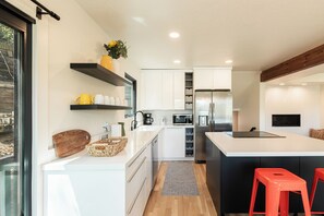 Eine moderne Küche mit weißen Schränken, einer zentralen Kochinsel, roten Barhocker und einem großen Fenster.