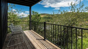 Une terrasse en bois avec des rampes en métal et deux chaises en métal.