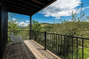 Eine Holzterrasse mit Metallgeländern und zwei Metallstühlen.