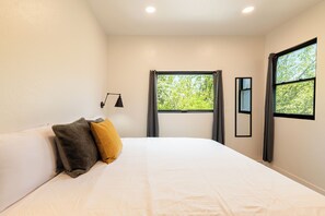 A bedroom with a bed, a nightstand, a lamp, and two windows with curtains. - 2BR mountain-view condo in Old Town Park City with balcony, fireplace, Wi-Fi (Park City)