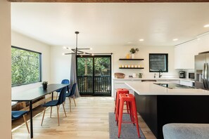 A modern kitchen with a large island, wooden flooring, and a dining area with chairs and a table. - 2BR mountain-view condo in Old Town Park City with balcony, fireplace, Wi-Fi (Park City)