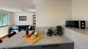 Eine moderne Küche mit Mikrowelle, Kaffeemaschine und Schneidebrett mit Gemüse.