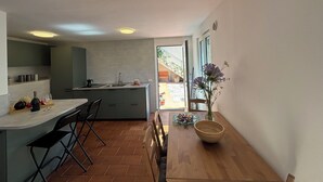 Eine moderne Küche mit Essbereich, einem Holztisch und Blick ins Freie.