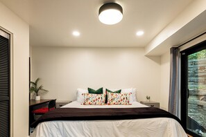 Une chambre à coucher avec un lit, deux oreillers, une table de chevet, une lampe et une fenêtre.