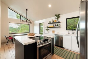 A modern kitchen with a large island, built-in oven, stainless steel appliances, and large windows offering views of greenery. - 2BR mountain-view retreat in Historic Old Town Park City (Park City)
