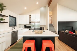 A modern kitchen with white cabinets, a stainless steel refrigerator, and a central island with stools.
