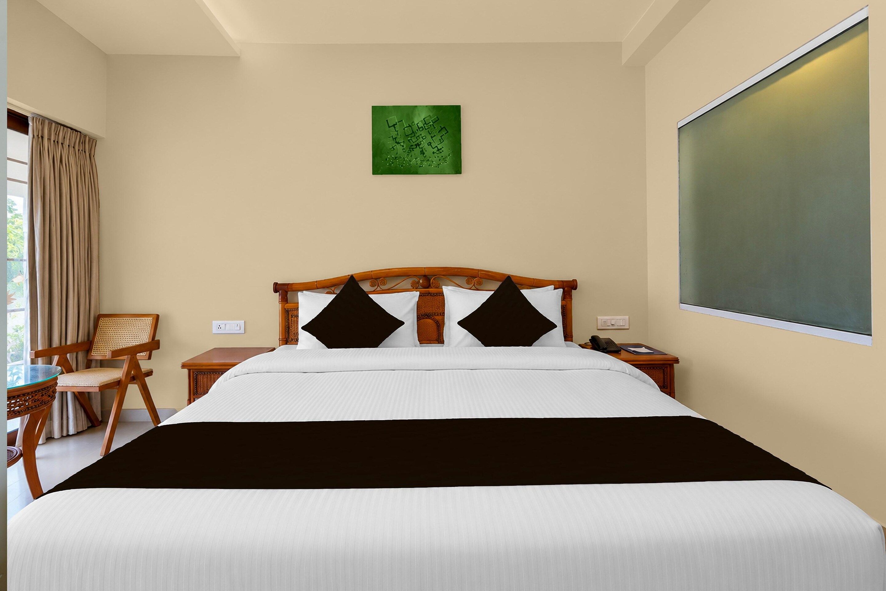 Una habitación de hotel con cama, mesita de noche, silla, mesa y ventana.