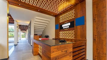A reception desk with a wooden finish, a patterned wall, and a sign indicating 'PALETTE OYO-Serviced'.