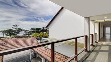 A modern building with a glass balcony overlooking a tiled roof and a body of water.