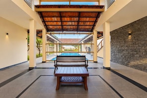 Zona junto a la piscina con un banco, un muro de piedra y vistas a la piscina.