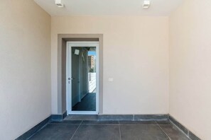 A corridor with a door leading to an outdoor area. - KeyRoom • Patio & Parking near Lake Como (Como)