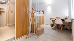 A modern bedroom with a wooden wardrobe, a desk with a chair, and a shower area. - Garden & Private Entrance – Ponte Milvio Loft (Rome)
