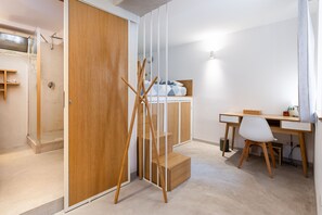 Ein modernes Schlafzimmer mit einem Holzschrank, einem Schreibtisch mit Stuhl und einer Duschkabine.