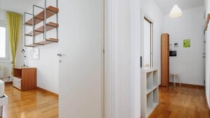 A modern interior with a wooden floor, white walls, a built-in shelf unit, and a hanging pendant light. - Porta Venezia Apt: 30s to Metro, Easy Airport (Milan)