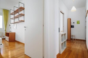 Ein modernes Interieur mit Holzboden, weißen Wänden, einer eingebauten Regaleinheit und einer hängenden Pendelleuchte.