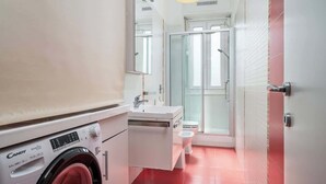 A compact bathroom with a washing machine, a sink, and a toilet. - Porta Venezia Apt: 30s to Metro, Easy Airport (Milan)