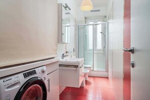 Ein kleines Badezimmer mit Waschmaschine, Waschbecken und Toilette.