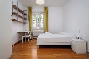 A bedroom with a bed, bedside table, desk, chair, and a window with curtains. - Porta Venezia Apt: 30s to Metro, Easy Airport (Milan)