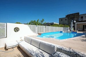 Una piscina amb una zona de gandules blanques i un edifici al fons.