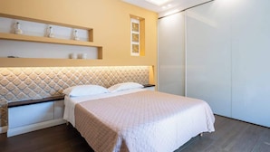 A modern bedroom with a bed, a headboard with a diamond pattern, a shelf with decorative items, and a sliding door closet. - Above the Ruins - a Dream of Baia (Bacoli)
