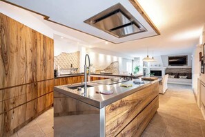 A modern kitchen with a central island, stainless steel appliances, and a wooden accent wall. - Above the Ruins - a Dream of Baia (Bacoli)