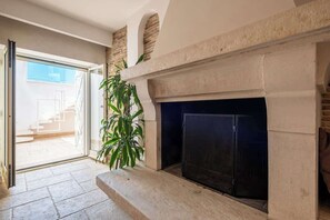 A room with a fireplace, a staircase leading to an outdoor area, and a potted plant. - Above the Ruins - a Dream of Baia (Bacoli)