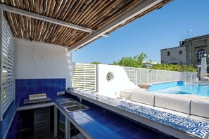 A poolside area with a built-in kitchen, a pool, and a view of the surrounding buildings. - Above the Ruins - a Dream of Baia (Bacoli)