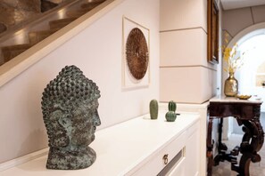 A statue on a white console table, a framed artwork on the wall, and a staircase in the background. - Above the Ruins - a Dream of Baia (Bacoli)
