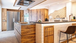 A modern kitchen with wooden cabinetry, a built-in island, and a stainless steel refrigerator. - Above the Ruins - a Dream of Baia (Bacoli)