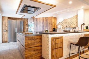 A modern kitchen with wooden cabinetry, a built-in island, and a stainless steel refrigerator. - Above the Ruins - a Dream of Baia (Bacoli)