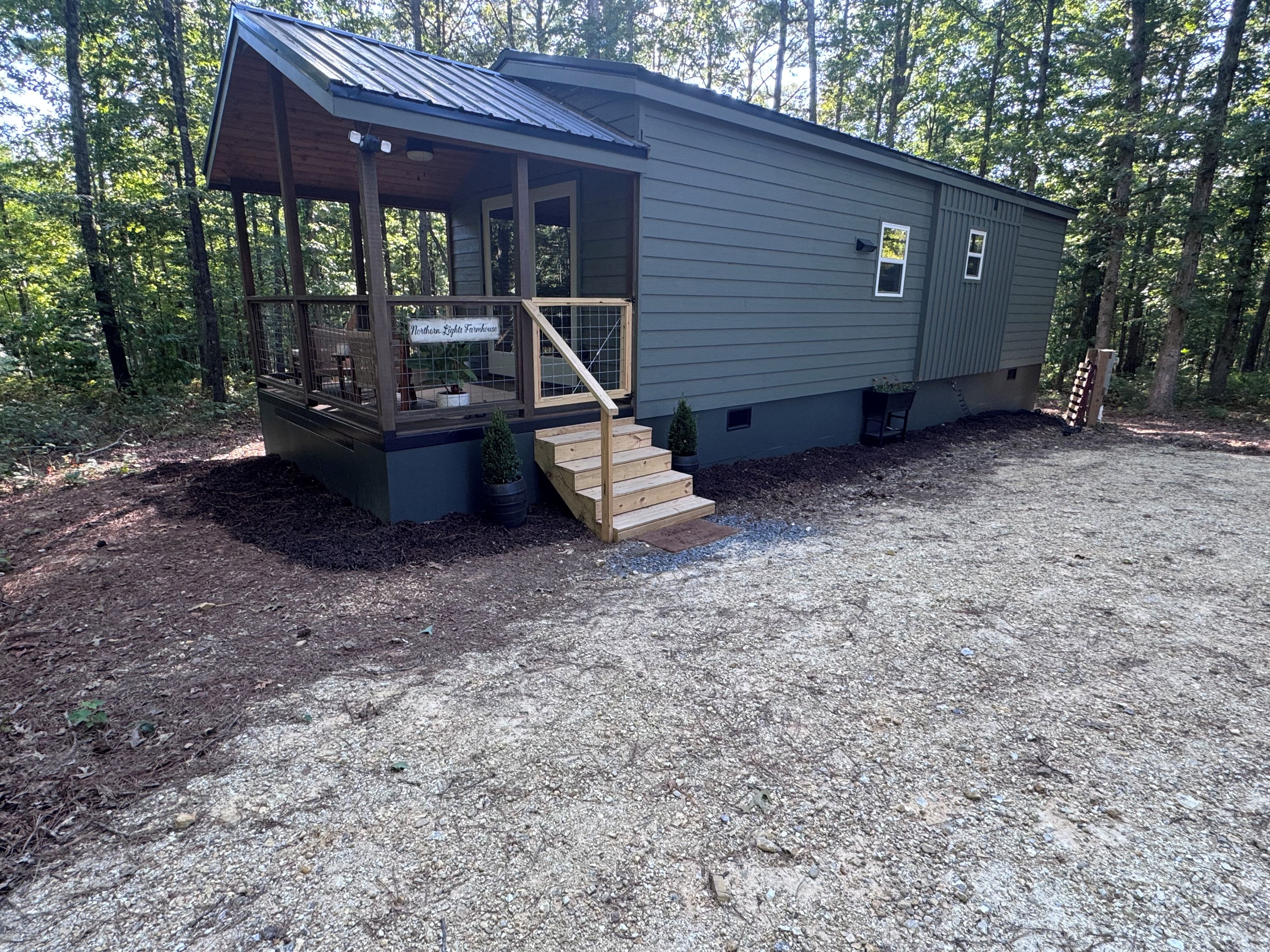 A small, single-story building with a porch and a sign that reads 'Northern Lights Farmhouse.'