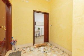 A hallway with a yellow wall, a wooden door, and a tiled floor. - Comfy&Stylish Apt in Rome (Rome)