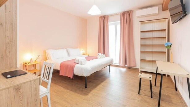 A bedroom with a bed, bedside tables, a desk, and a chair. - Comfy&Stylish Apt in Rome (Rome)