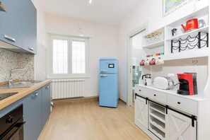 A modern kitchen with a blue refrigerator, white cabinets, and a countertop with a coffee machine. - Comfy&Stylish Apt in Rome (Rome)